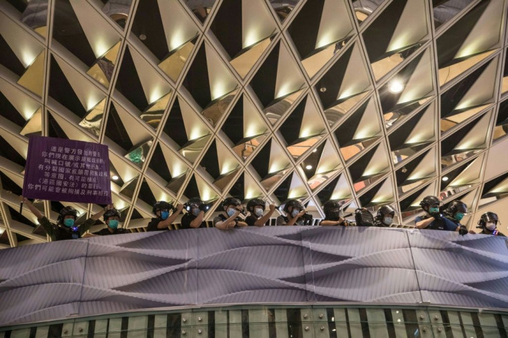 Riot police wave a banner warning protesters are breaking Beijing's new security law