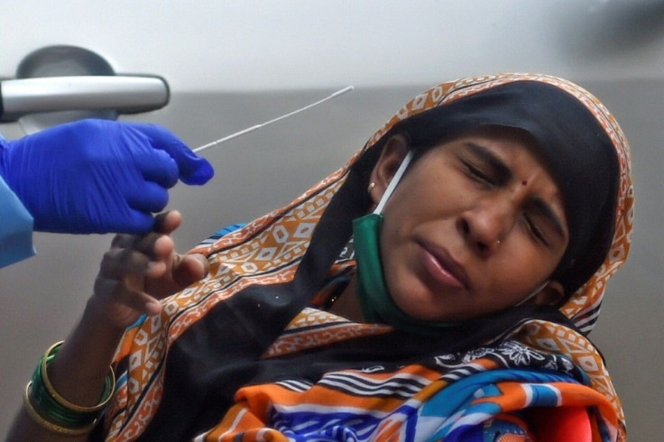 A health worker prepares to collect a swab sample from a woman as she reacts during a medical screening for the COVID-19 coronavirus, at a residential building in Mumbai on July 22, 2020.India last week became the third country after the United States and