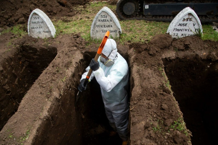 A worker wearing biosecurity equipment digs graves for alleged victims of the new coronavirus Covid-19, at the San Diego Cemetery in Quito