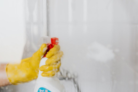person-in-glove-spraying-detergent-at-walk-in-shower-glass-4239101