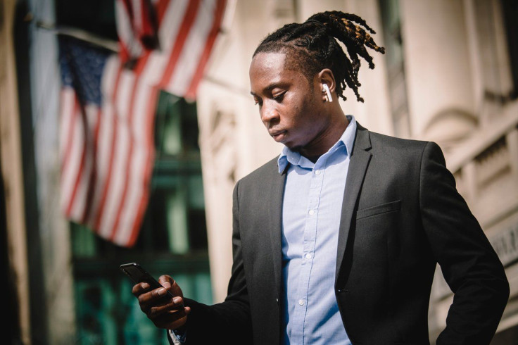 serious-black-businessman-using-smartphone-on-street-4560146