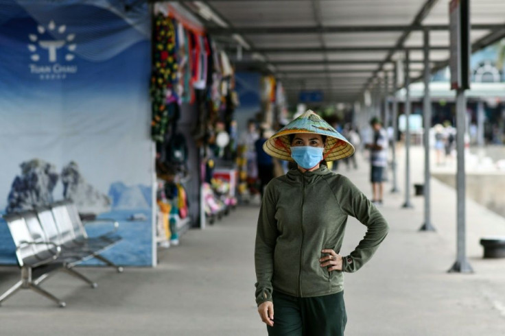 A woman wearing a face mask walks along the Tuan Chau harbour in Ha Long Bay, Vietnam