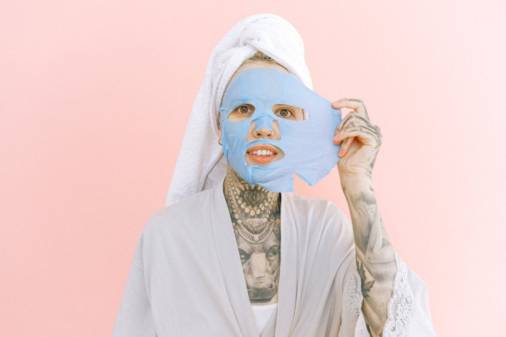 woman-with-tattoos-removing-collagen-mask-from-face-3852161