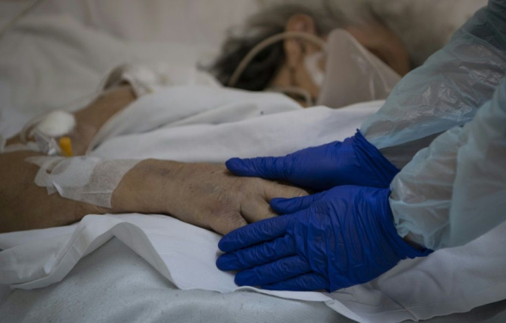 Dr Moyra Lopez holds the hand of a terminally ill patient at the Barros Luco hospital ward in Santiago where loved ones are able to see dying patients even if they have contracted the coronavirus