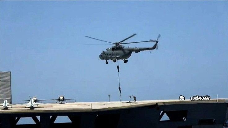 An image grab shows soldiers rappelling down from a Russian-made Iranian military helicopter on to a mockup of a US aircraft carrier during a military exercise
