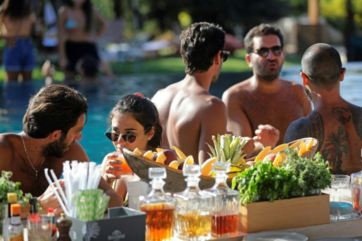 Around a long swimming pool at the club, bronzed bodies sprawled on sofas and sun loungers, some sipping cocktails, as music blasted in the background