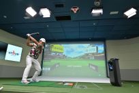 A South Korean golfer hits in a simulation booth during the GTour screen golf tournament in Daejeon, south of Seoul