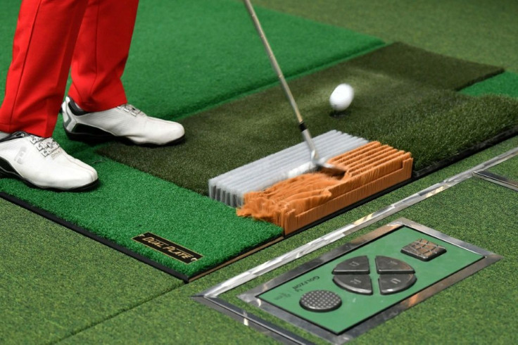 A players splashes out from a deep-pile mat to simulate a sandy lie in a bunker