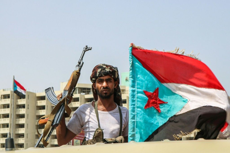 A fighter of the UAE-trained Security Belt Force, dominated by supporters of renewed independence for south Yemen, poses with a Kalashnikov and the old southern flag