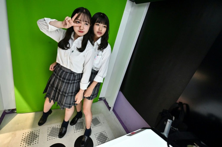 Teenagers in Tokyo pose at a Japanese photo booth known as a "purikura"