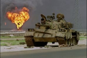 An abandoned Iraqi Soviet-made T-62 tank sits in the Kuwaiti desert as an oil well burns in the background, on April 2, 1991