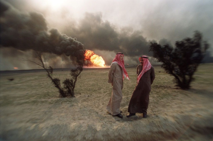 Two Kuwaiti men walk in the al-Ahmadi oil field, where wells were set ablaze by retreating Iraqi troops, in March 1991