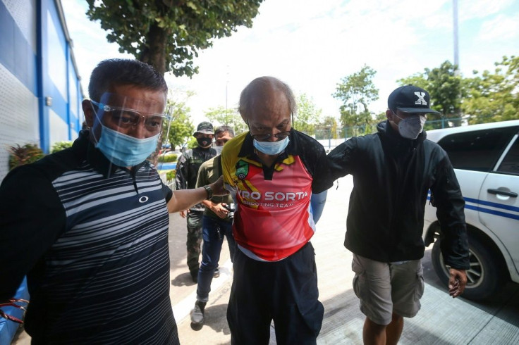 Ruben Ecleo is escorted by officers outside police regional headquarters in Manila, following his arrest