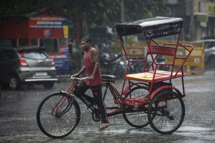 A rickshaw driver rides along a street during monsoon rainfall in New Delhi