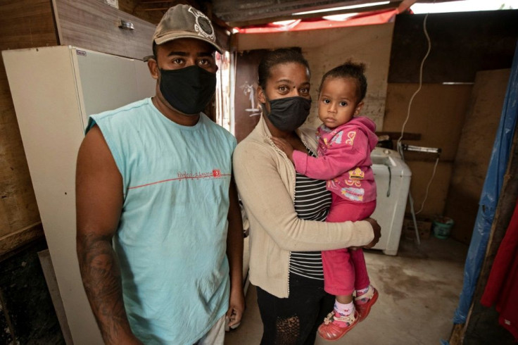 Residents os the Jardim Julieta favela, Gilmar Goncalves Chaves (L), his wife Joyce Aparecida Ribeira Pinto and their daughter Kemelly pose at their home in the outskirts of Sao Paulo, Brazil, on July 15, 2020