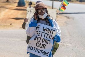 Zimbabwean novelist Tsitsi Dangarembga holds a placard during an anti-corruption march along Borrowdale road, in Harare; she was arrested and freed on bail the following day