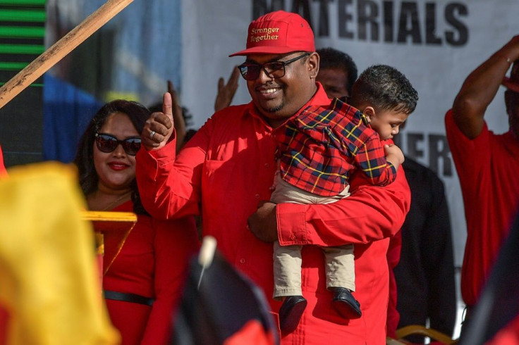 Irfaan Ali holds his son as he arrives at a campaign rally in Lusignan, Guyana on February 29, 2020