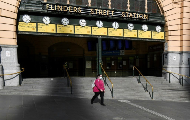A woman walks out of a near-deserted Flinders Street Station in Melbourne after the state announced new restrictions to contain coronavirus