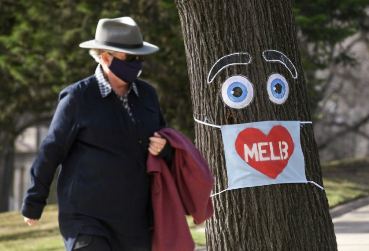 A man walks past a virus-theme decorated tree in Melbourne