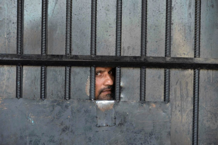 A man watches from behind a closed gate after a raid at the prison in Jalalabad