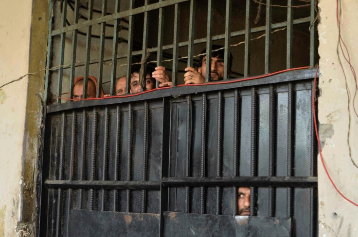 Inmates peer out from behind a gate at the prison in Jalalabad