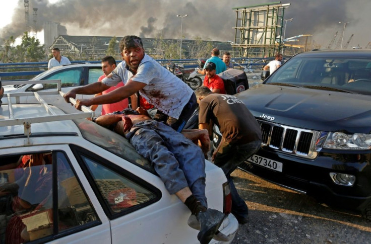 An injured man lies at the back of a car before being rushed away from the scene of a massive explosion at the port