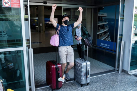 A traveller, mask-clad due to the COVID-19 coronavirus pandemic, arriving on one of the first flights from Britain gestures as he walks with luggage out of the terminal at Cyprus' Larnaca International Airport on August 1