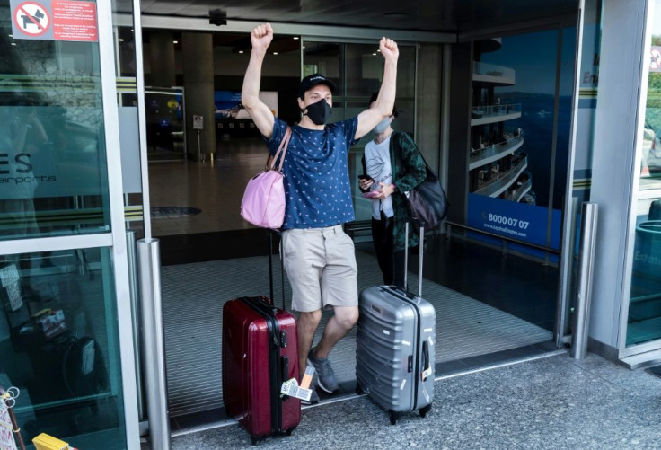 A traveller, mask-clad due to the COVID-19 coronavirus pandemic, arriving on one of the first flights from Britain gestures as he walks with luggage out of the terminal at Cyprus' Larnaca International Airport on August 1