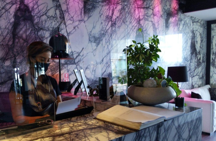 A mask-clad hotel receptionist checks in visitors at a hotel reception in the southern Cypriot port city of Larnaca