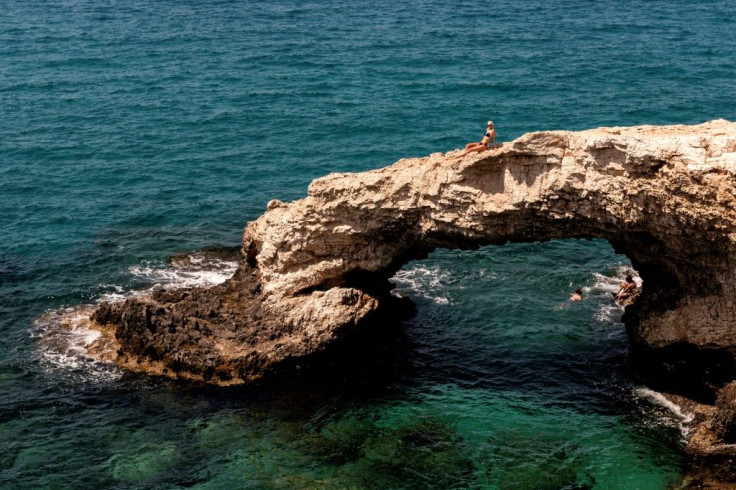 A lone tourist sits above the "Love bridge" off the Cypriot Mediterranean resort of Ayia Napa