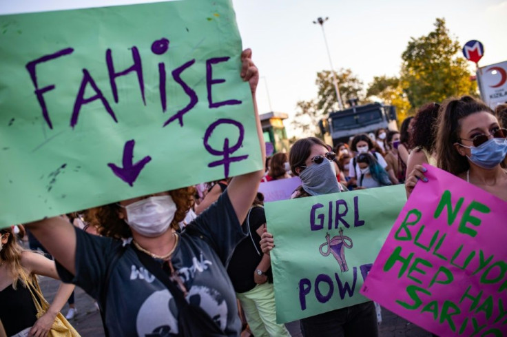 Demonstrators wearing protective face masks hold up placards reading "Whore" (L) and "Girl Power" during a demonstration for a better prevention of violence against women, in Istanbul, Turkey