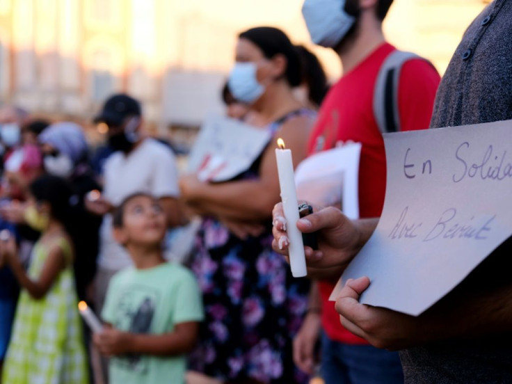 A man holds a sign reading "Solidarity with Beirut" and a candle on August 5, 2020 in Toulouse, during a gathering to pay tribute to the Lebanese people a day after a powerful explosion tore through Lebanon's capital