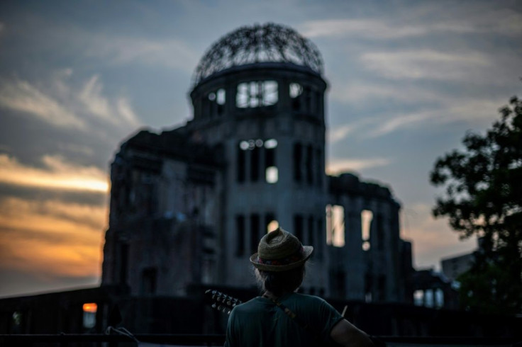 A man plays his guitar in front of  the Hiroshima Prefectural Industrial Promotion Hall, now commonly known as the atomic bomb dome