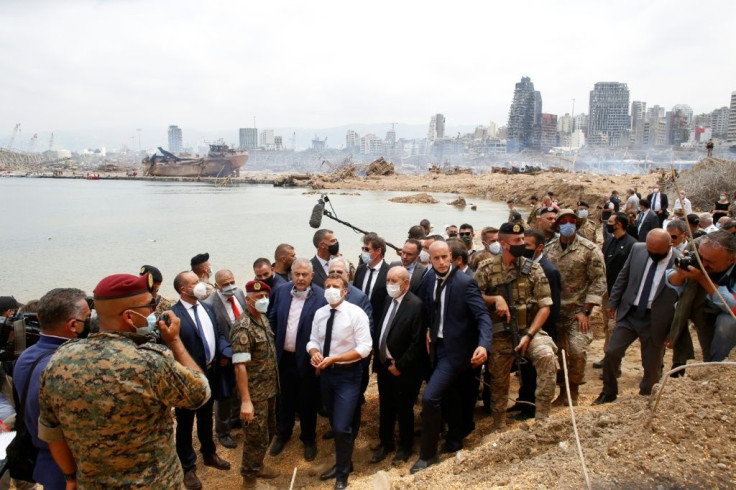 French President Emmanuel Macron (C), with French Foreign Minister Jean-Yves Le Drian, visits the devastated site of the explosion at the port of Beirut