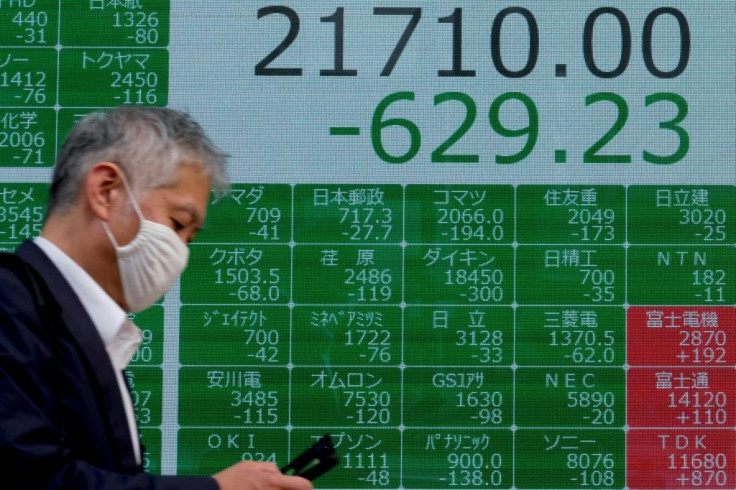 A man walks past a board displaying share prices in Tokyo