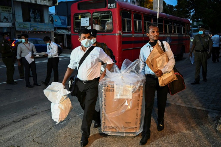 Sri Lankan election officials take a ballot box to a counting centre after the parliamentary election voting sites closed