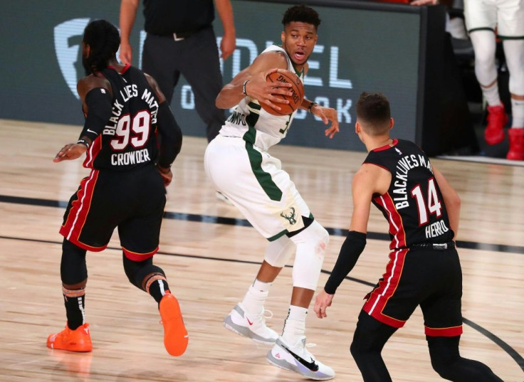 Milwaukee Bucks forward Giannis Antetokounmpo, center, moves the ball against Miami's Jae Crowder, left, and Tyler Herro in a 130-116 victory Thursday that clinched a top seed for the NBA playoffs for the Bucks