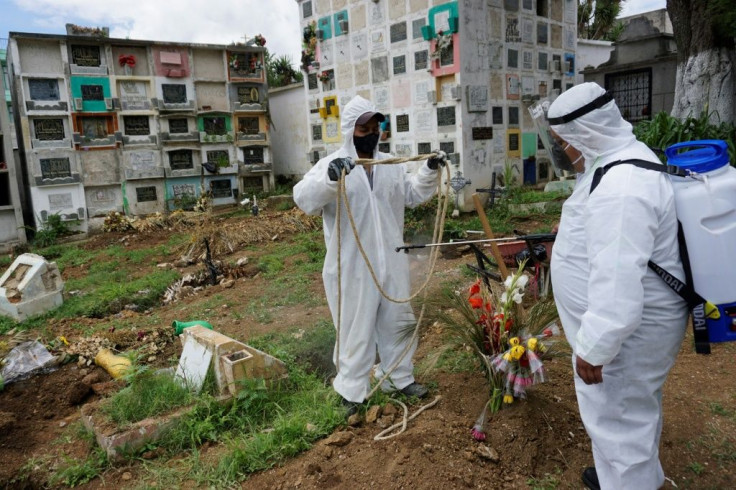 Gravediggers wearing biosafety suits disinfect a rope used to bury a coffin containing a COVID-19 victim at the Mixco municipal cemetery 20 kilometers from Guatemala City on August 6, 2020
