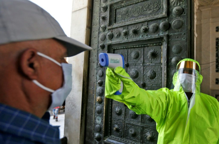 A medic outside Damascus's Umayyad Mosque checks the temperatures of worshippers before they are allowed to enter