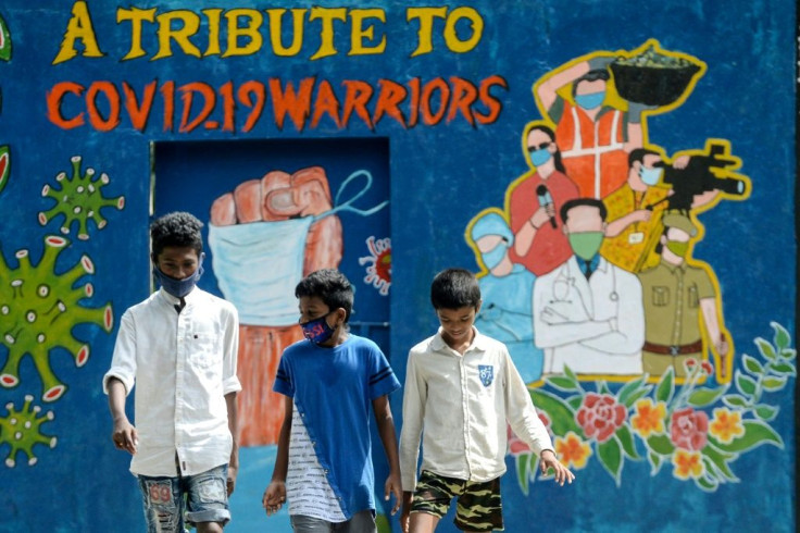 Youths walk past a mural dedicated to frontline workers fighting against the spread of the COVID-19 coronavirus, in Chennai.