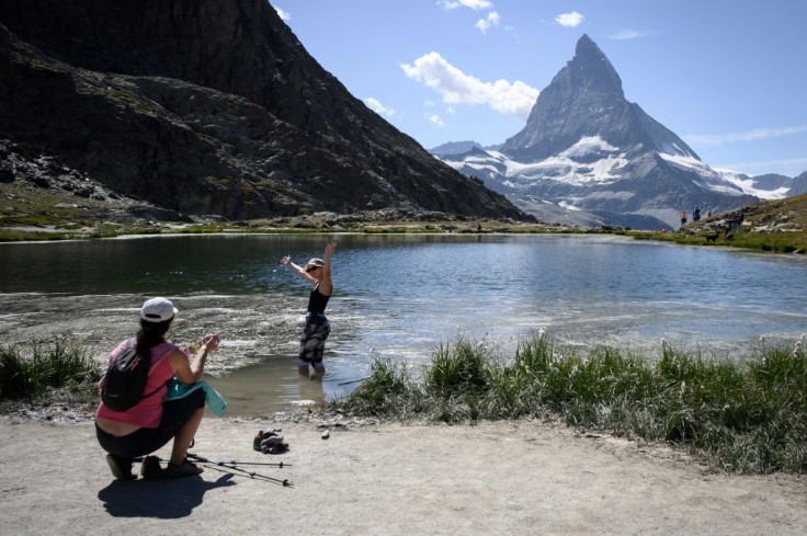 A tourist poses for a picture in the Riffelsee mountain lake with the Matterhorn mountain in background above the resort of Zermatt as heatwave sweeps across Europe