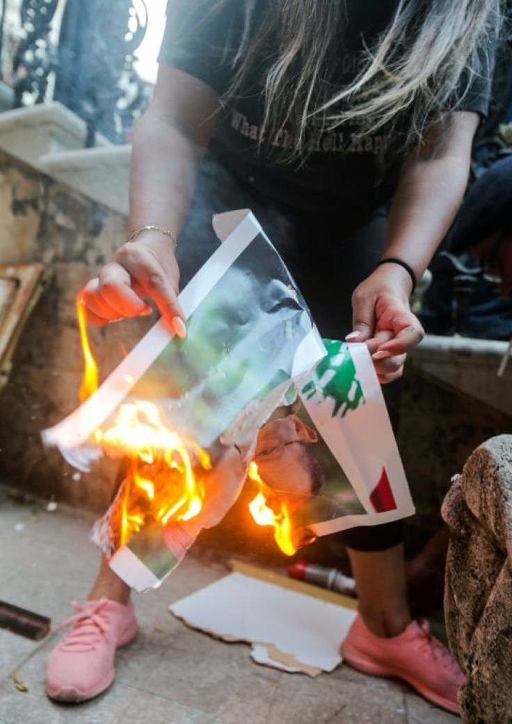 A Lebanese protester in the ministry burns a picture of President Michel Aoun