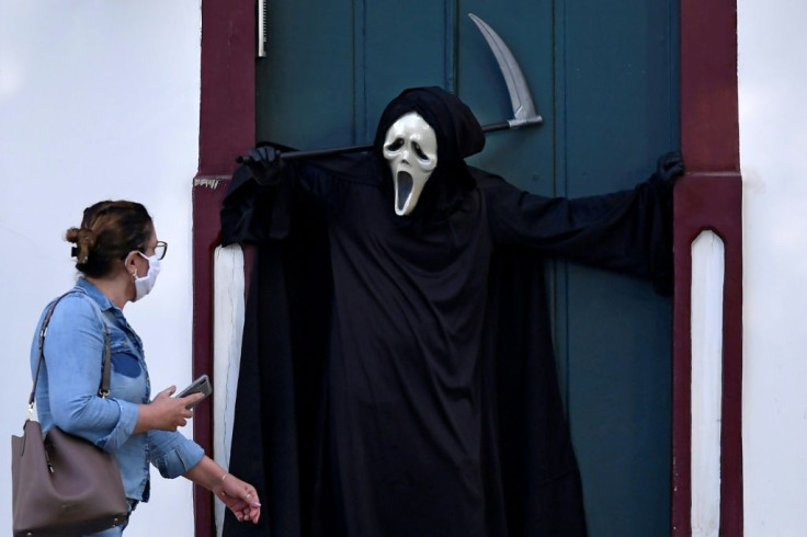 A woman looks at Brazilian actor Fabio de Almeida disguised as death to raise awareness of the importance of wearing face masks and  social distancing,  in Formiga, Minas Gerais