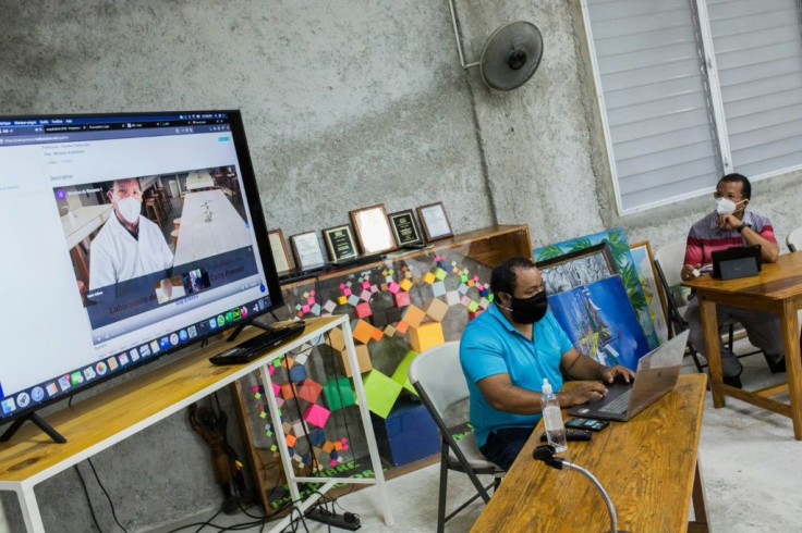 Guy Etienne (R), principal of the Catts Pressoir middle school in Port-au-Prince, demonstrates the Haiti school's internet platform, along with his son, Guy Philippe Etienne, who teaches robotics at the tech-focused school