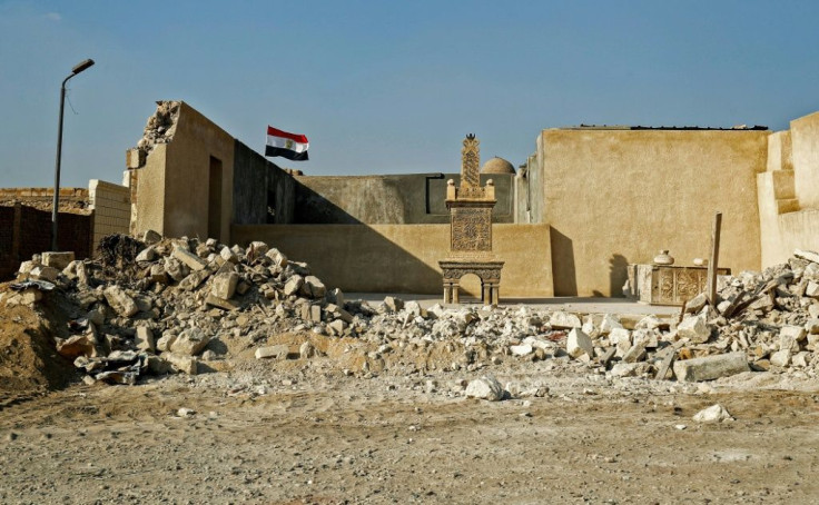 An Egyptian flag behind a grave marker, exposed by the destruction of a surrounding wall in the historic City of the Dead necropolis in Egypt's capital Cairo