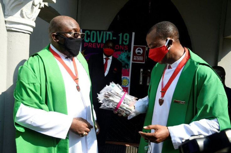 A priest holds a pack of face masks outside a church in Lagos following the reopening of churches and lifting of restrictions on religious gatherings by the Nigerian government