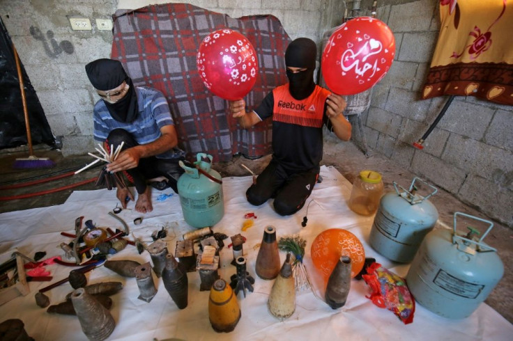 Masked Palestinians prepare flammable objects before attaching them to balloons to be flown towards Israel, in Rafah in the southern Gaza Strip