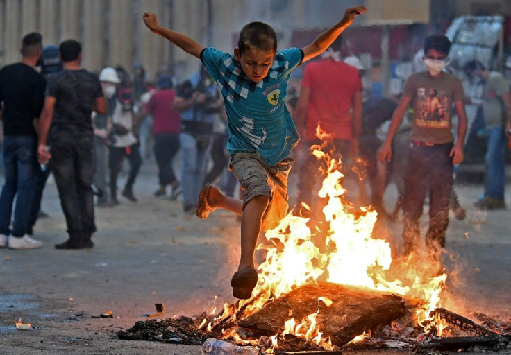 A Lebanese boy jumps over a fire during clashes between protesters and security forces near the parliament in central Beirut on August 10