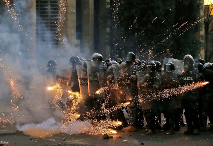 Firecrackers thrown by protesters explode in front of riot police amid clashes near the parliament in central Beirut