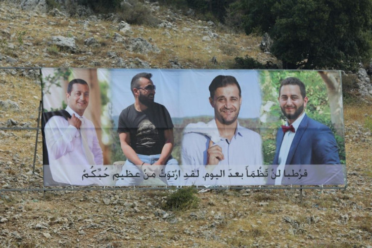 A banner with portraits of four victims from the same Lebanese mountain town who have been missing since Beirut's massive port explosion, displayed at the entrance of Qartaba in the Byblos district, north of the Lebanese capital